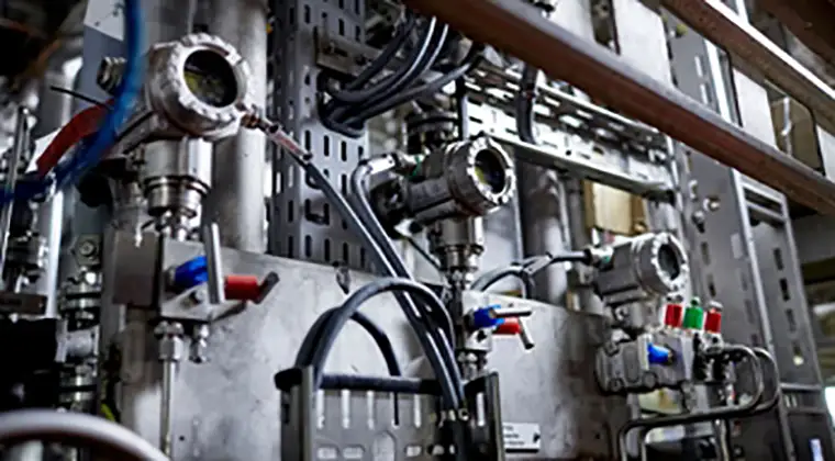 A close-up view of an intricate industrial machine with multiple pipes, valves, and cables.