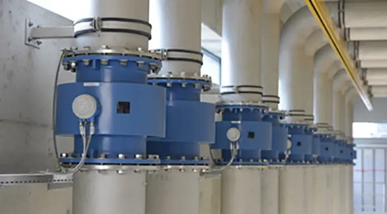 A row of industrial blue valves attached to white pipes in a well-lit facility.