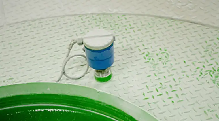 A blue and white sensor with a cable attached, placed on a textured white surface near a green circular object.