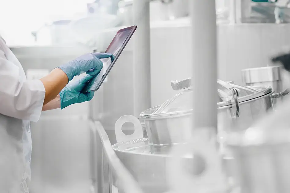 A laboratory technician using a tablet in front of a industrial boiler.